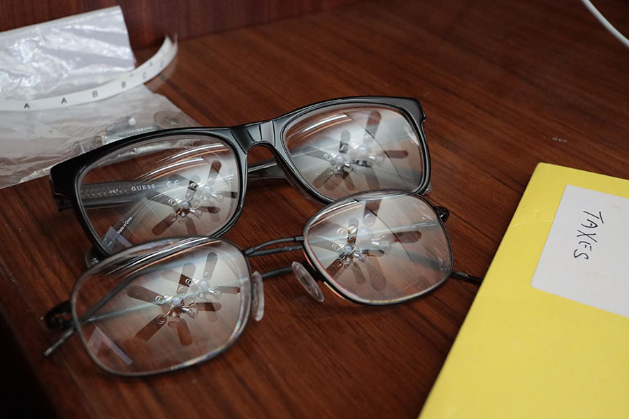 Two Pairs of Glasses on Desk With Reflected Ceiling Fans